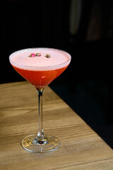 a red cocktail with rose on a brown table