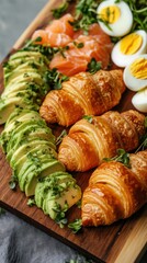Low-angle shot of a wooden board with golden croissants, fresh avocado, boiled eggs, salmon, and microgreens. Vibrant, dynamic presentation with natural light and rustic warmth