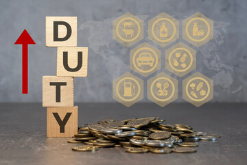 Drewniane kostki z napisem Duty obok sterta monet . Koncepcja wzrostu ceł. © siwyk