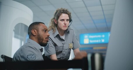 Airport Staff at Security Checkpoint: Two Multiethnic TSA Officers Talking, Monitoring Screening Procedures for Boarding Flight Using Computer. Transportation Security Administration for Travel Safety