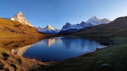 Fototapeta premium Serene alpine lake reflecting majestic snow-capped peaks at sunrise