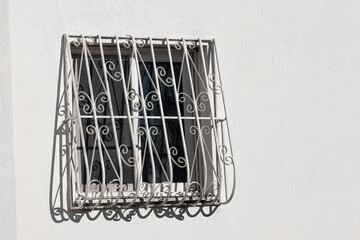 Window with guards and security bars on house wall. Forged metal protective grille on a window