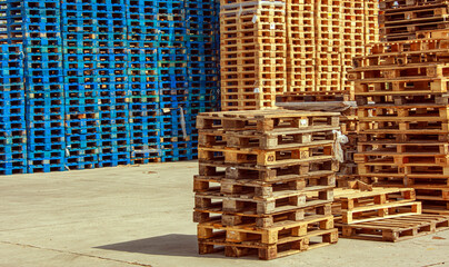 Stacks of wooden pallets are neatly arranged in various formations, with some painted blue while...