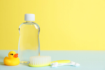 Baby oil, rubber duck, brush and cotton swabs on color background. Space for text