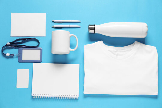 Different blank items for branding on light blue background, flat lay. Mockup for design