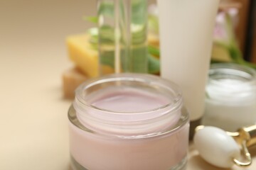 Different body care products and face roller on beige background, closeup