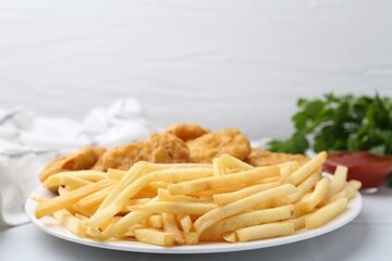 Tasty chicken nuggets and french fries with sauce on white tiled table, closeup. Space for text