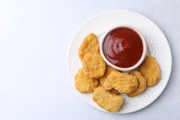 Tasty chicken nuggets with sauce on white background, top view. Space for text