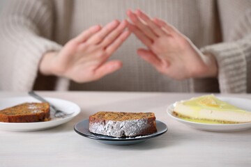 Woman refusing to eat products at table indoors, selective focus. Food allergy concept