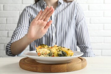 Woman refusing to eat piece of casserole at table, closeup