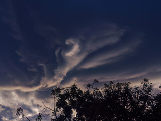 A big peculiar gray dense cloud hanging at sunrise over the farm lands of the eastern Andean mountains of central Colombia, before a rainstorm.