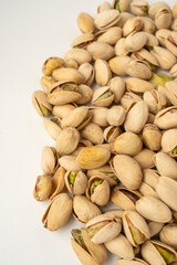 A lot of salted pistachios on white background, isolated, top view, crunchy roasted nuts, tasty and nutritious snack, healthy organic food, high-protein vegetarian ingredient, in-shell pistachio