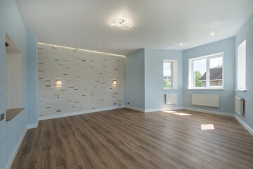 A bright empty room with a bay window in a private house. Brown laminate floor. Unfurnished.