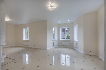 An empty open space with windows in a private house. A room with a final finish, floor tiles. Unfurnished.