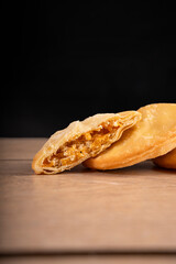 Empanadas de pollo y queso: contraste dorado sobre fondo negro