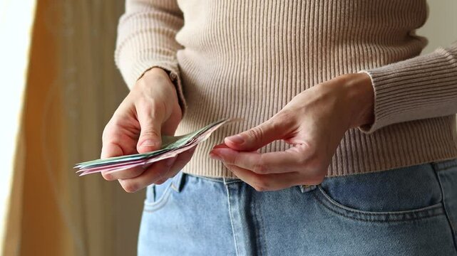 Close up view of woman's hands holding Thai baht (THB) cash money banknotes. Concept of saving money for retirement, cash settlement, financial success, literacy and income planning in Thailand.