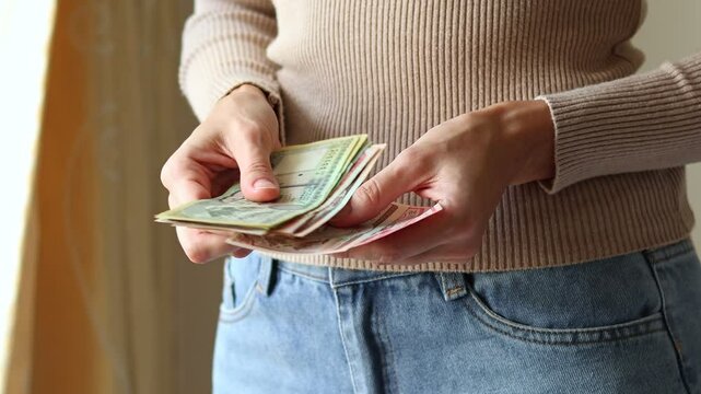 Close up view of woman's hands holding Nepalese rupee (NPR) cash money banknotes. Concept of saving money for retirement, cash settlement, financial success, literacy and income planning in Nepal.