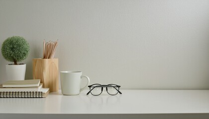 desk with stationery, eyeglasses, notebook, mug and a plant, copy space