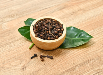 Dried herb, dried cloves in wood bowl  on wood table.