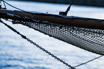 close-up of a ship’s bowsprit with netting and chains.
