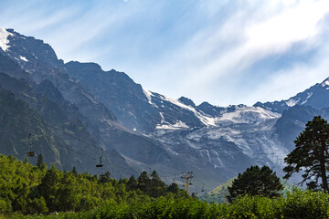 Fototapeta premium Cable car ascending snowy mountain peaks in summer