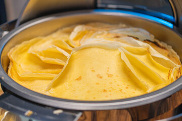 Image depicts a cooked flatbread or pancake with bananaplantain slices on an electric griddle, evenly heated and arranged in a circular pattern