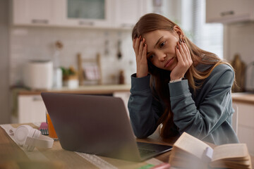 Exhausted female student using laptop while e-learning at home.