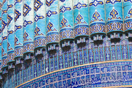 Turquoise Islamic Tile on Blue Mausoleum Dome cracked wall showcases geometric and floral patterns on sunny day. Traditional middle eastern architecture with vibrant blue and azure hues on patina