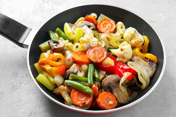 Different vegetables and mushrooms in frying pan on grey table, closeup