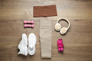 Flat lay composition with women's sportswear and athletic equipment on wooden background