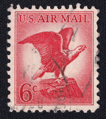 Old vintage cancelled postage stamp printed in the USA circa 1963 with an illustration of the iconic Bald Eagle. Macro image of the stamp on a black background.