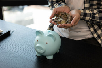 A man is managing the money he has saved in a piggy bank to pay his bills.
