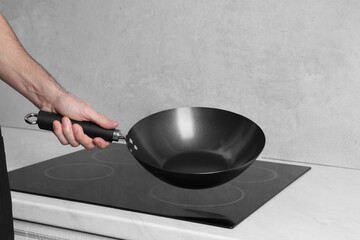 Chef holding frying pan over cooktop in kitchen, closeup