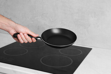 Chef holding frying pan over cooktop in kitchen, closeup