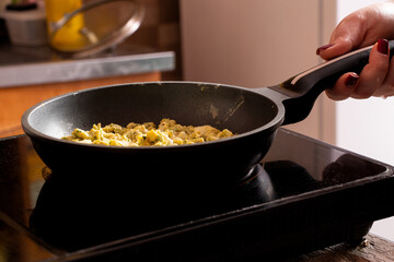 Girl holding frying pan in kitchen on induction hob and cooking