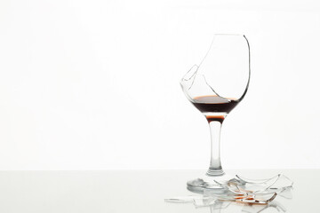 Pieces of broken glass with wine on table against white background, space for text