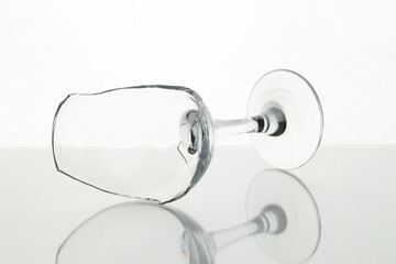 One broken wine glass on table against white background, closeup