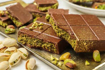 Pieces of Dubai chocolate bars with pistachios and knafeh on white table, closeup