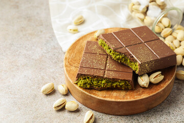 Pieces of Dubai chocolate bar with pistachios and knafeh on grey table, closeup. Space for text