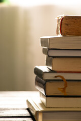 A stack of books lies on a wooden table at home