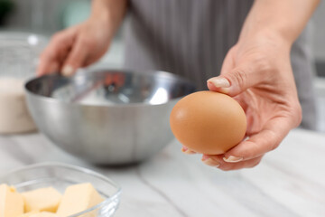 Making dough. Woman with fresh egg at white marble table, closeup