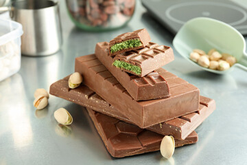 Stack of tasty Dubai chocolate bars with pistachios and knafeh on grey table, closeup