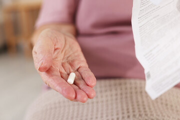 Senior woman with medical instruction and pill, closeup