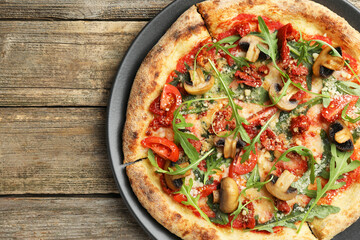 Tasty pizza with mushrooms, tomatoes and arugula on wooden table, top view. Space for text