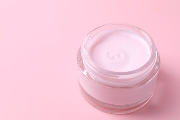 Jar of moisturizing cream on pink background, closeup. Space for text