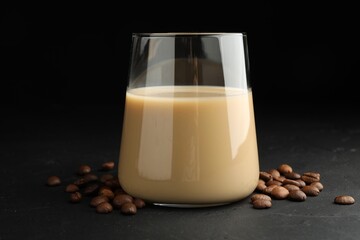 Coffee cream liqueur in glass and beans on black table