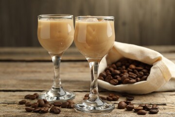 Coffee cream liqueur in glasses and beans on wooden table, closeup