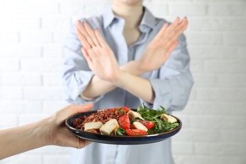 Naklejka premium Woman refusing to eat meal near white brick wall, selective focus. Food allergy concept