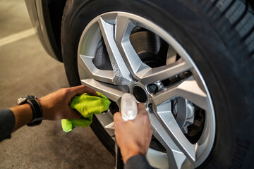 Close up of man's hands spraying rims with rim detergent and cleaning it with rag.