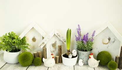 Easter decorative composition, home decoration for the bright Easter holiday. On a light background, cute chickens and wooden houses, front view, Easter style.